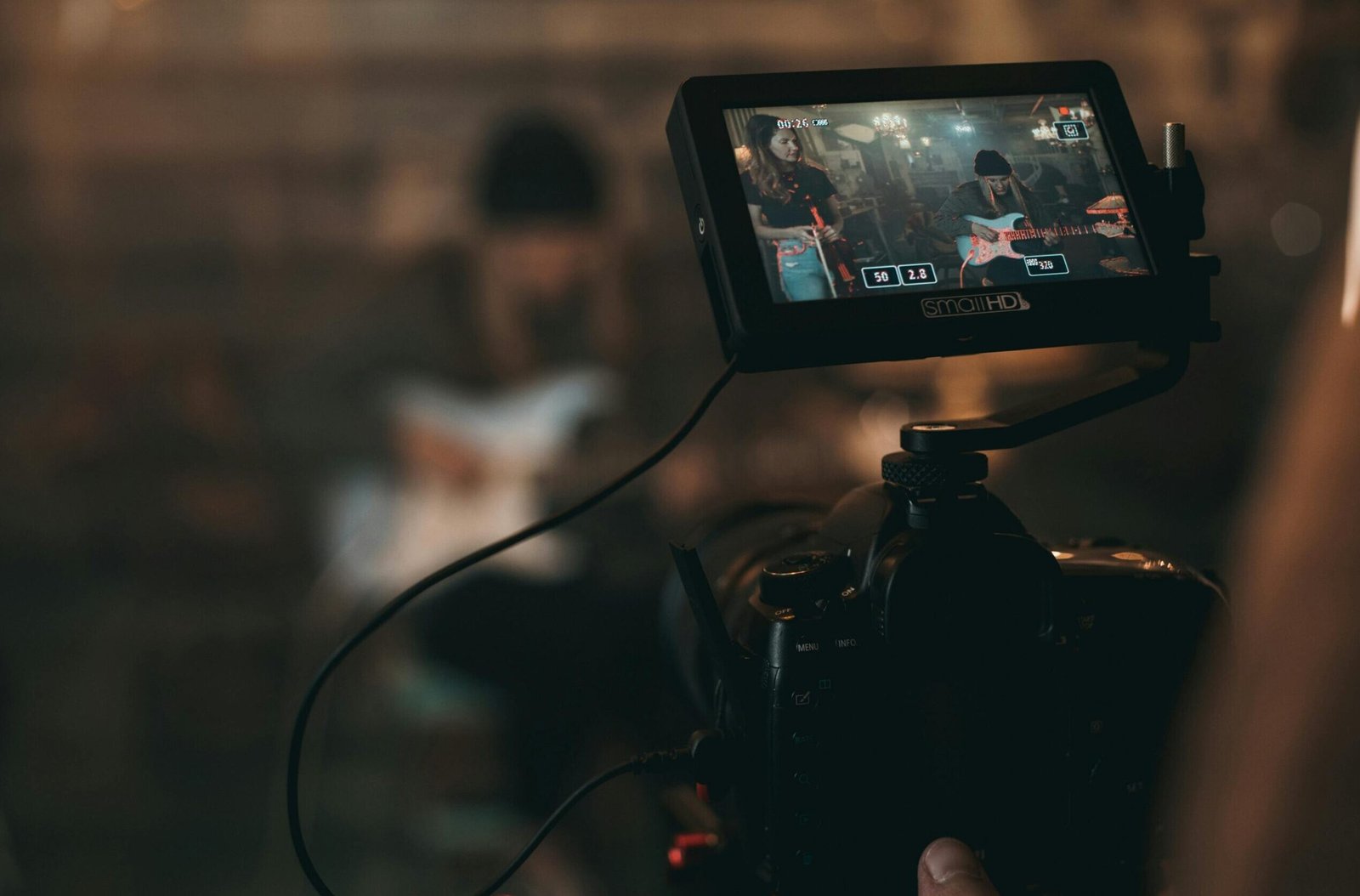 A cinematic close-up of filming a rock band performance with focus on camera screen.